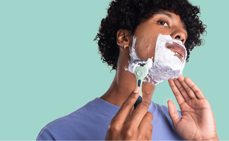 person shaving their face with shaving cream on