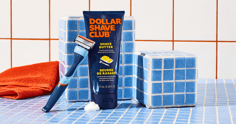 Dollar Shave Club product with a razor and soap on a tiled bathroom floor.